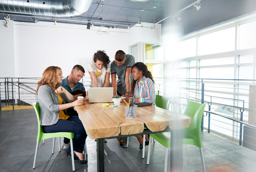 Multi ethnic group of succesful creative business people using a laptop during candid meeting Multi ethnic group of succesful creative business people using a laptop during candid meeting